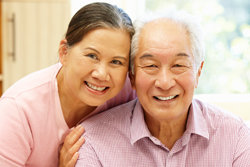 A happy elderly Asian couple smiling wearing a pink shirt
